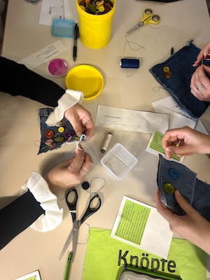 Hände üüber einem Tisch, die Knöpfe sortieren